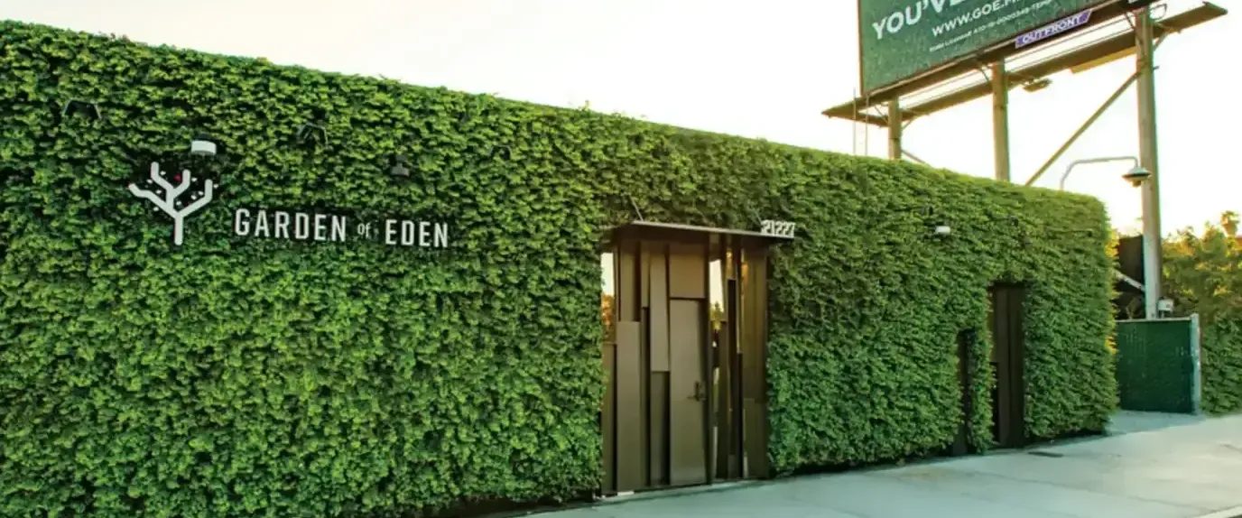 Garden of Eden dispensary building covered in greenery with logo and billboard
